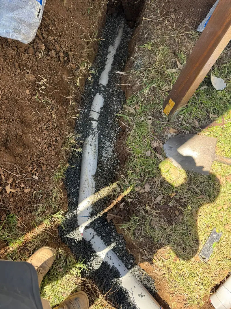 Exposed pipework supported in prepared bedding before backfilling.