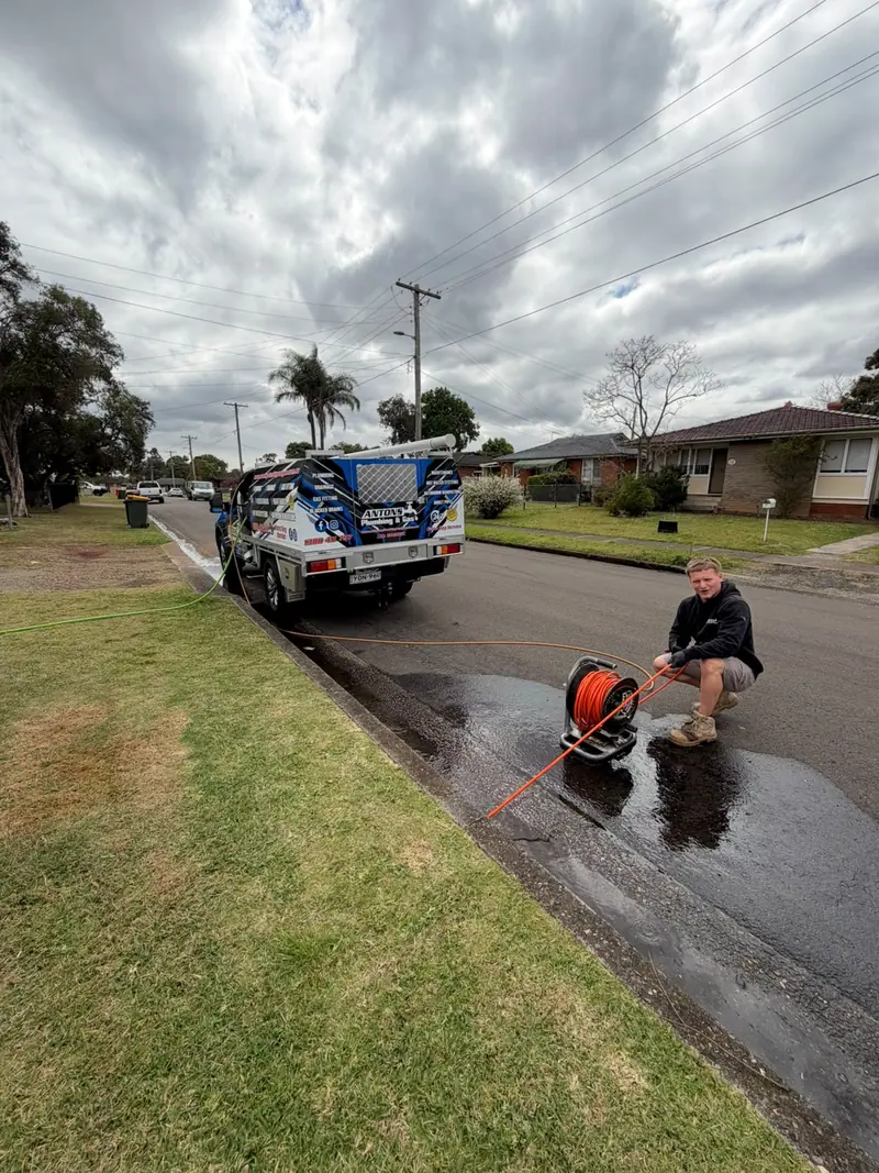 Antons technician with drain-clearing equipment beside the service vehicle